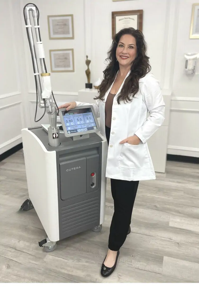 Bonnie Hinkle standing beside the enLIGHTen III laser at her clinic